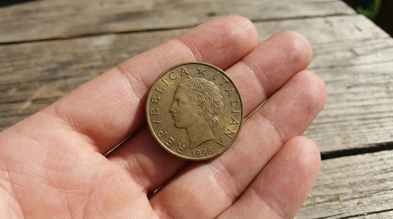 Moneta da 200 lire del 1996 tenuta tra le dita di una mano